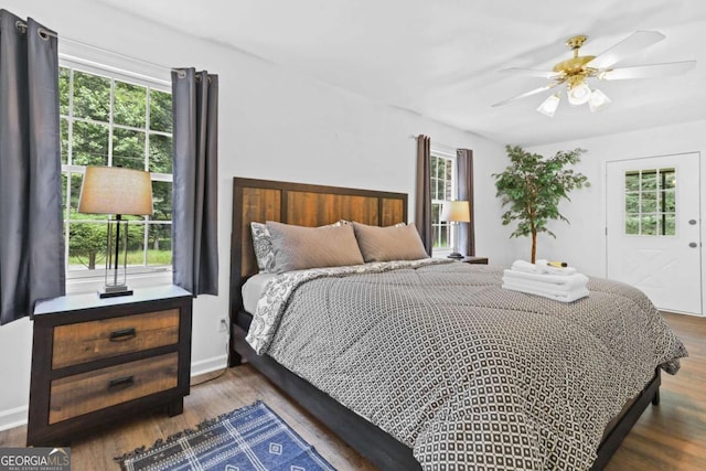 bedroom with multiple windows, dark wood-type flooring, and ceiling fan