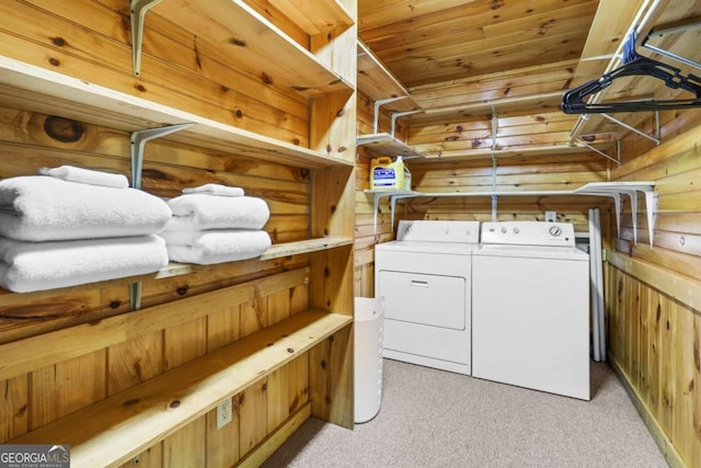 laundry area with wood ceiling, washing machine and dryer, light carpet, and wood walls