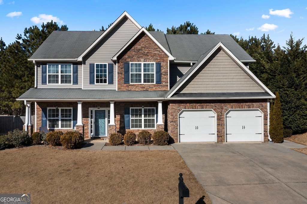 view of front facade featuring a garage, a front yard, and covered porch