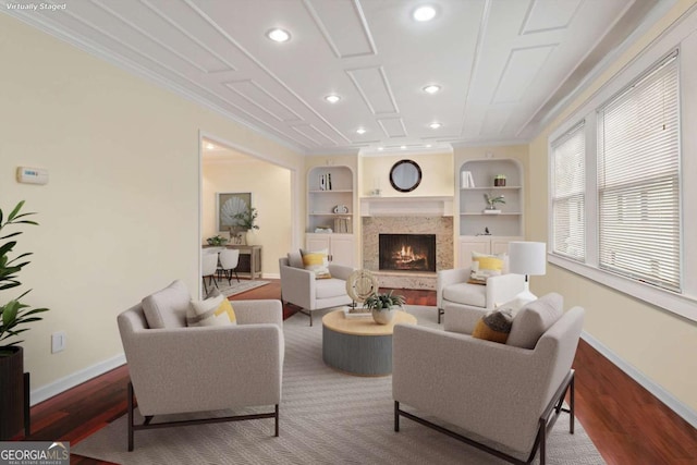 living room featuring hardwood / wood-style floors, built in shelves, a fireplace, and ornamental molding