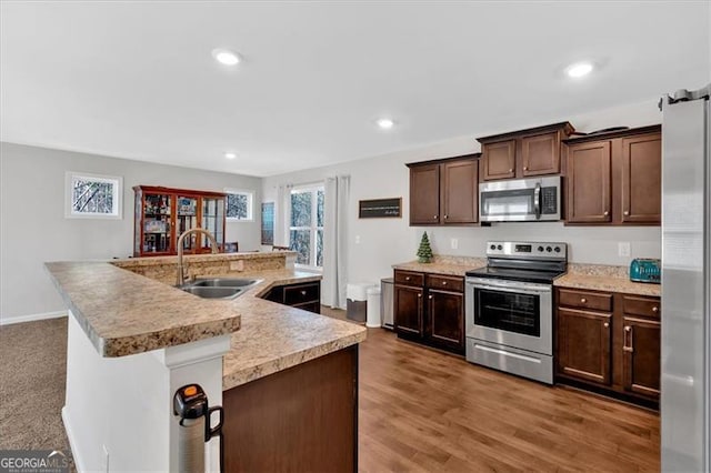 kitchen with dark brown cabinetry, sink, an island with sink, and appliances with stainless steel finishes