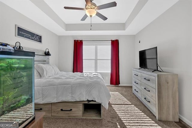 bedroom featuring dark carpet, a raised ceiling, and ceiling fan