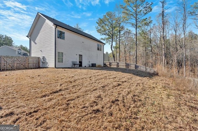 back of property with central AC and a lawn