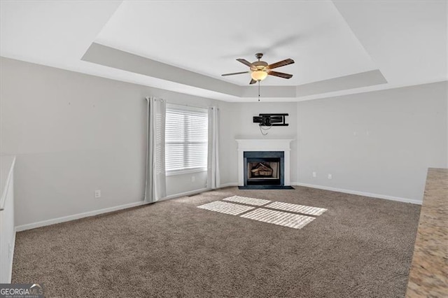 unfurnished living room featuring a raised ceiling, carpet floors, and ceiling fan