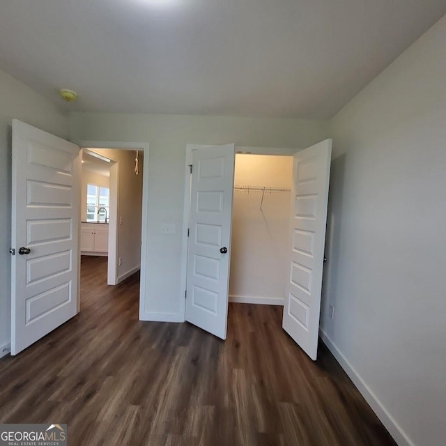 unfurnished bedroom with a closet, sink, and dark hardwood / wood-style floors