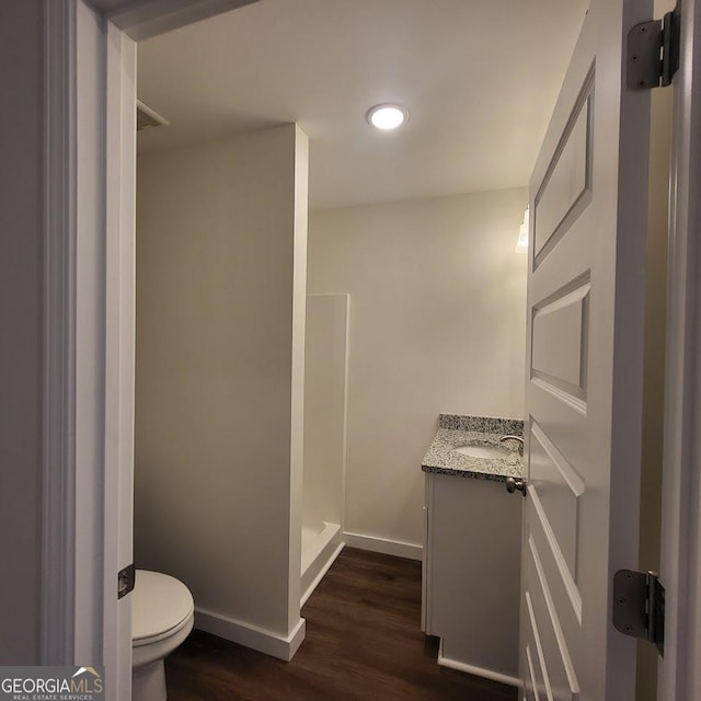 bathroom with walk in shower, wood-type flooring, vanity, and toilet