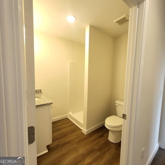 bathroom featuring vanity, hardwood / wood-style floors, a shower, and toilet