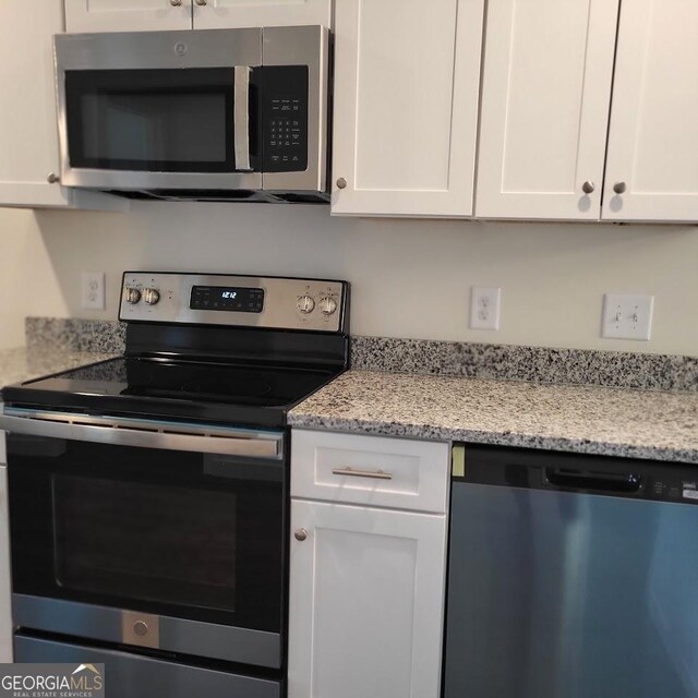 kitchen featuring light stone counters, stainless steel appliances, and white cabinets