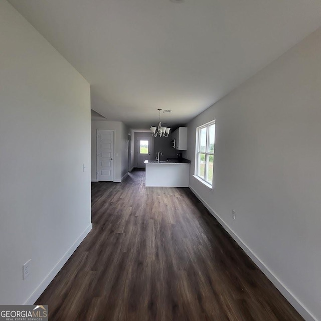 unfurnished living room featuring dark hardwood / wood-style flooring and an inviting chandelier