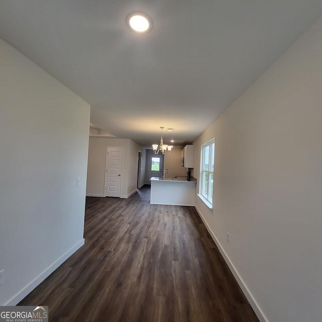 unfurnished living room with an inviting chandelier, dark hardwood / wood-style flooring, and sink