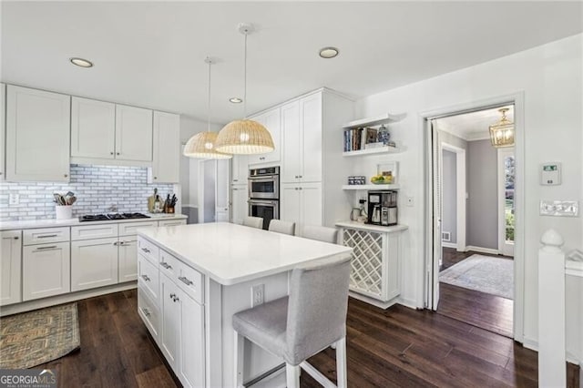 kitchen with stainless steel appliances, white cabinetry, a kitchen island, and pendant lighting