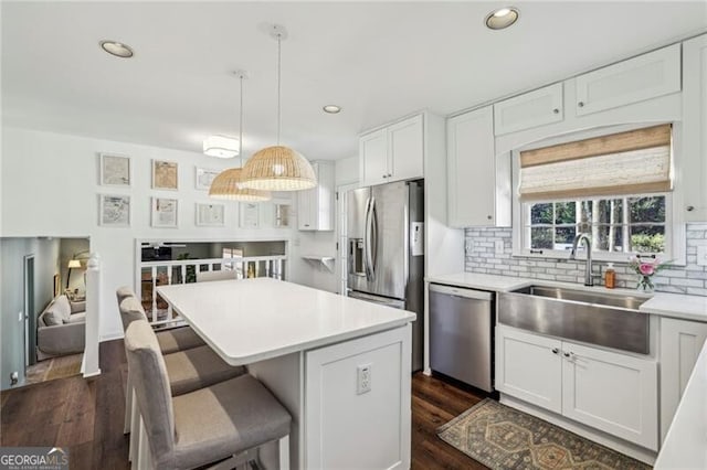 kitchen featuring sink, hanging light fixtures, stainless steel appliances, a center island, and white cabinets