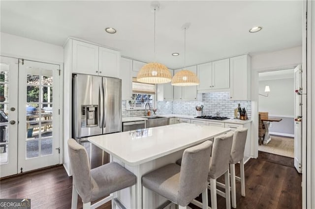 kitchen with appliances with stainless steel finishes, a kitchen island, hanging light fixtures, and white cabinets