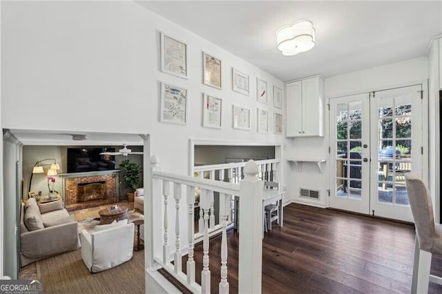 stairs with french doors, wood-type flooring, and a brick fireplace