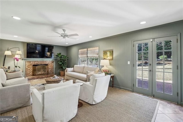 living room with french doors, ceiling fan, light tile patterned flooring, and a brick fireplace