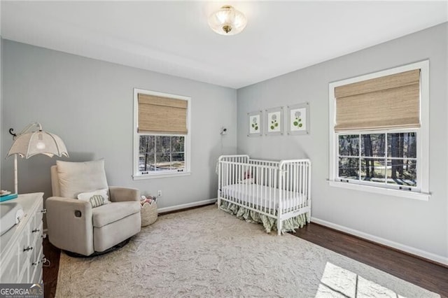 bedroom with hardwood / wood-style flooring, multiple windows, and a crib