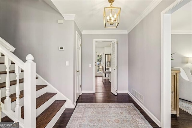 entrance foyer with a notable chandelier, ornamental molding, and dark hardwood / wood-style floors