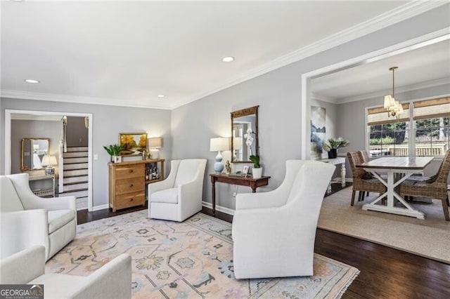 living room featuring hardwood / wood-style flooring, ornamental molding, and an inviting chandelier