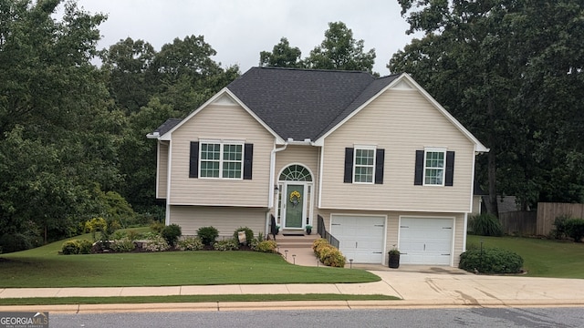 raised ranch featuring a garage and a front yard