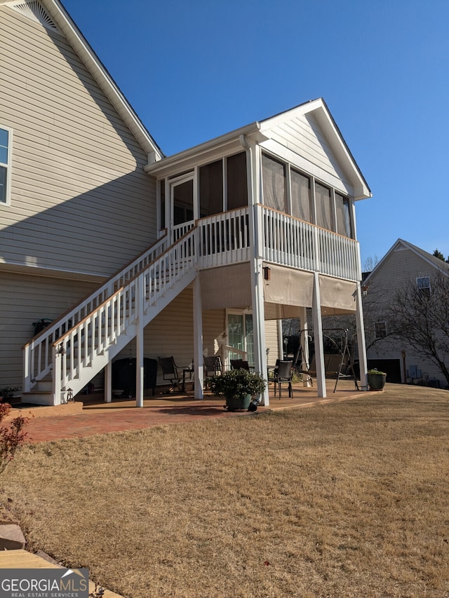 rear view of property with a patio area, a sunroom, and a lawn