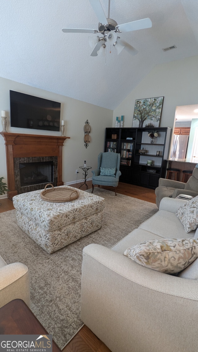 living room featuring vaulted ceiling, wood-type flooring, ceiling fan, and a textured ceiling