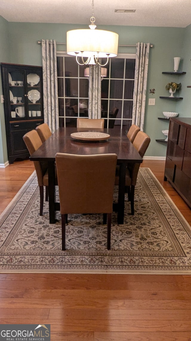 dining area featuring hardwood / wood-style floors, a textured ceiling, and a chandelier