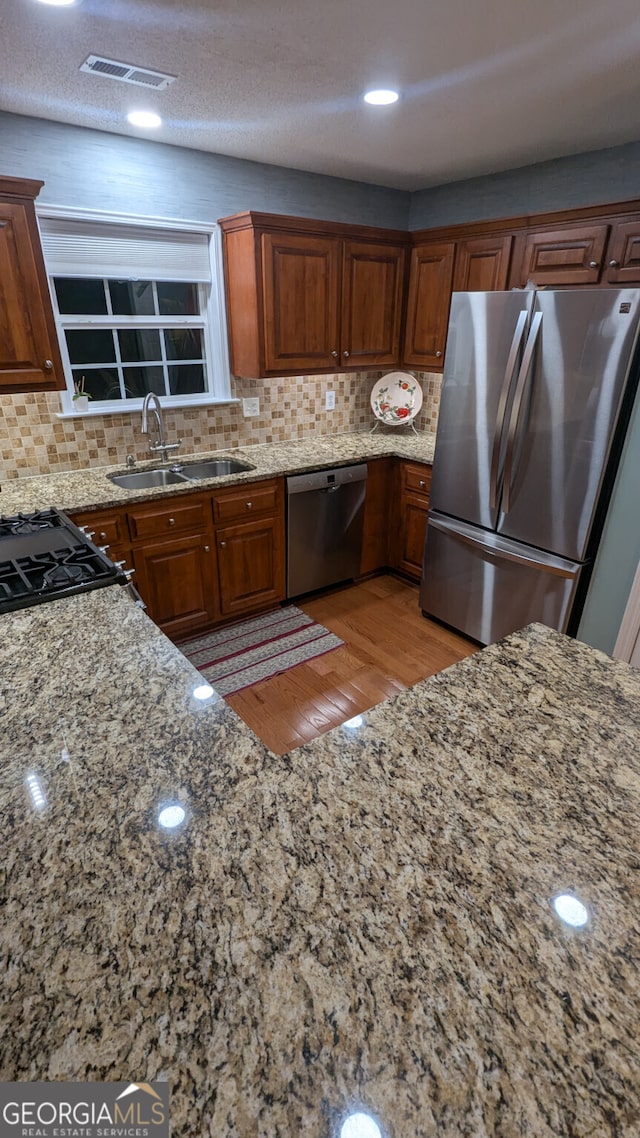 kitchen featuring stainless steel appliances, light stone countertops, and sink