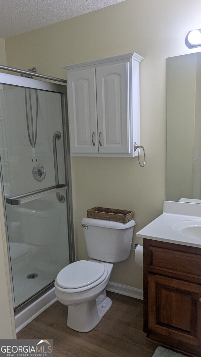 bathroom with vanity, an enclosed shower, wood-type flooring, a textured ceiling, and toilet