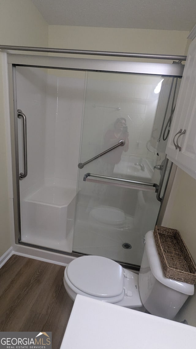 bathroom featuring wood-type flooring, toilet, and an enclosed shower