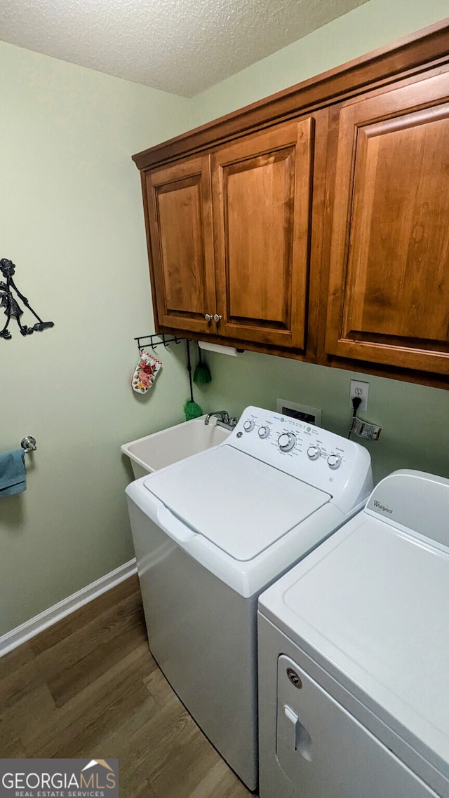 laundry area featuring sink, cabinets, washer and dryer, a textured ceiling, and dark hardwood / wood-style flooring