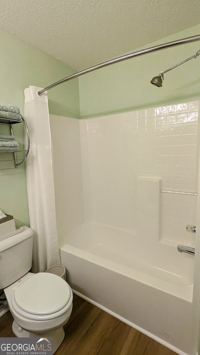 bathroom with hardwood / wood-style flooring, shower / bath combo with shower curtain, a textured ceiling, and toilet