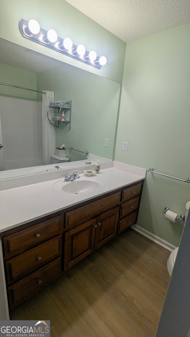 bathroom with vanity, hardwood / wood-style floors, toilet, and a textured ceiling