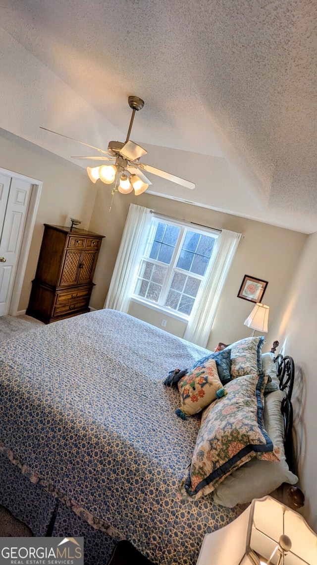 bedroom with ceiling fan, carpet, and a textured ceiling