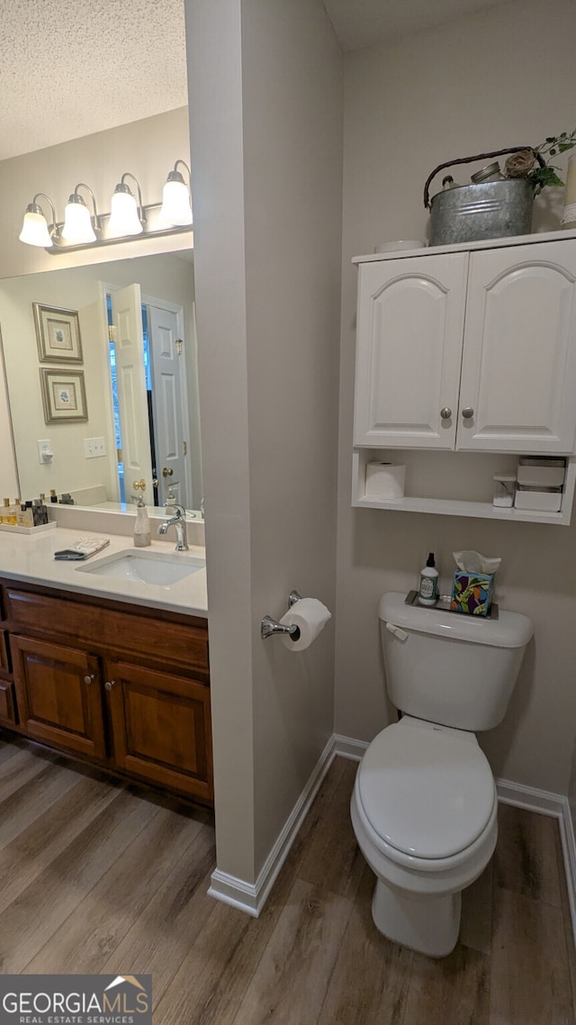 bathroom featuring hardwood / wood-style flooring, vanity, a textured ceiling, and toilet