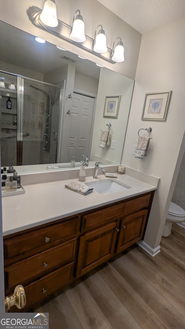 bathroom featuring toilet, an enclosed shower, a textured ceiling, vanity, and hardwood / wood-style flooring