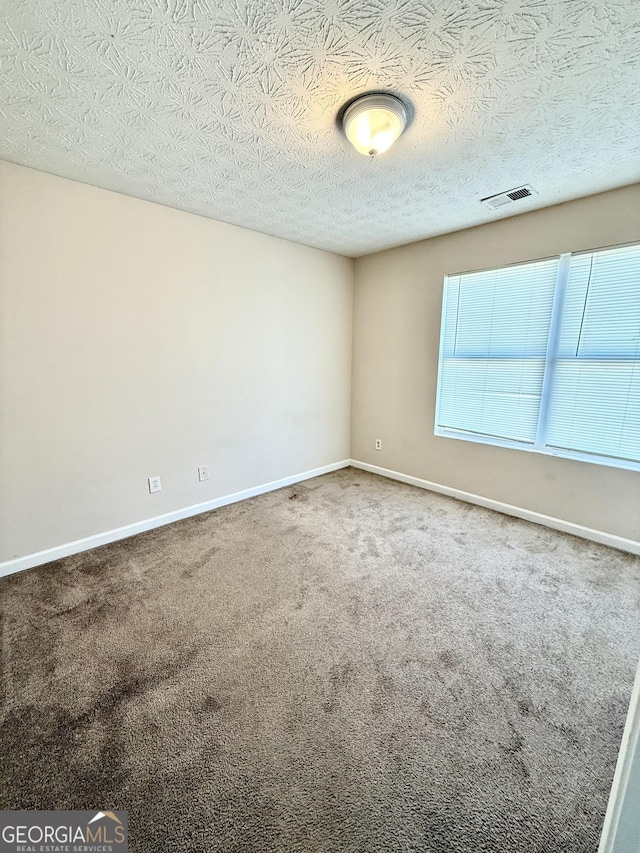 carpeted empty room featuring a textured ceiling