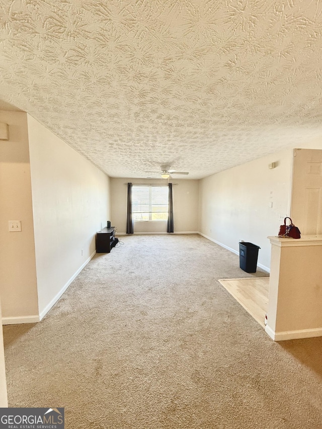 unfurnished living room with a textured ceiling, ceiling fan, and carpet