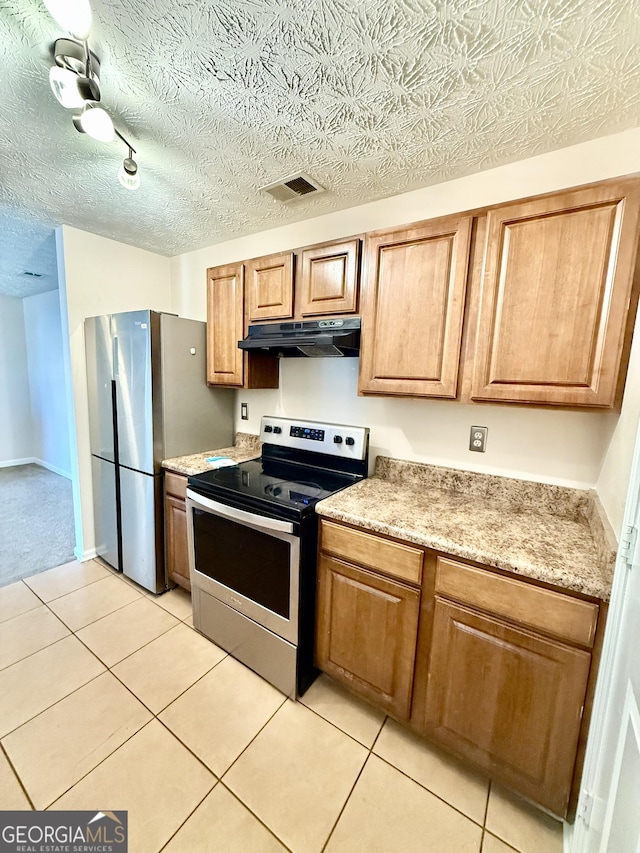 kitchen with appliances with stainless steel finishes, a textured ceiling, and light tile patterned floors