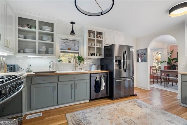 kitchen with stainless steel appliances, white cabinets, wood counters, and decorative light fixtures