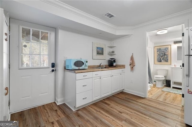 kitchen featuring crown molding, light hardwood / wood-style floors, sink, and white cabinets