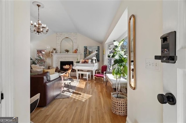 interior space with lofted ceiling, a brick fireplace, hardwood / wood-style floors, and a chandelier