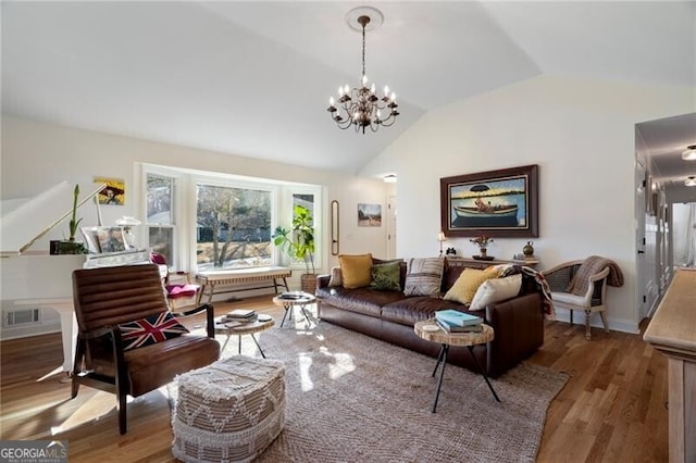 living room with hardwood / wood-style flooring, vaulted ceiling, and a notable chandelier