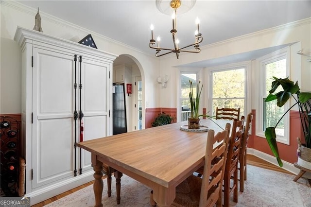 dining space with an inviting chandelier, ornamental molding, and light hardwood / wood-style flooring