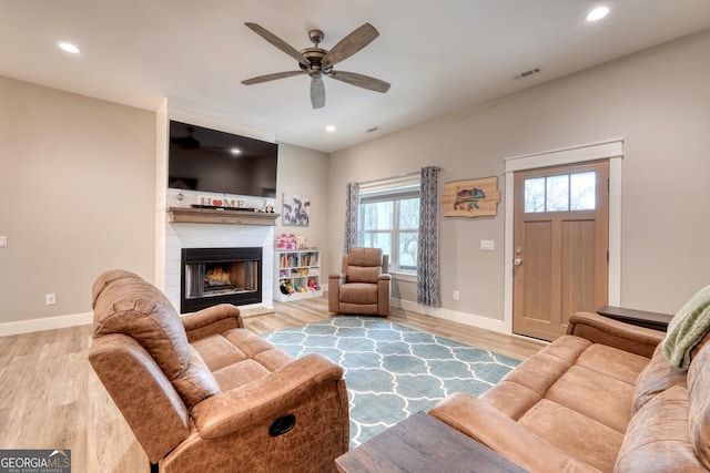 living room featuring hardwood / wood-style flooring, a fireplace, and ceiling fan