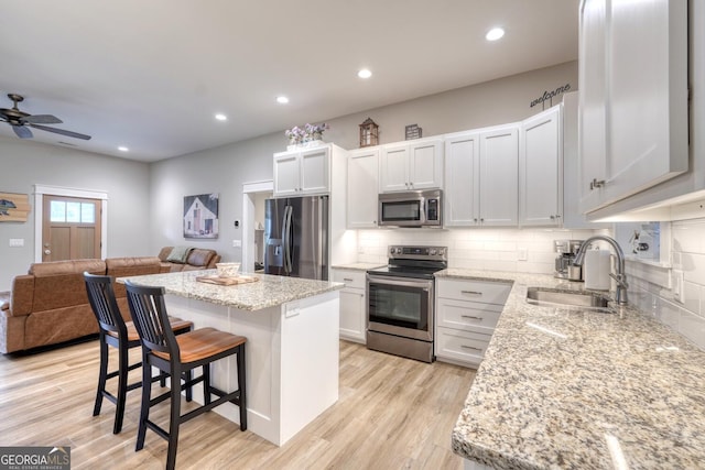 kitchen with stainless steel appliances, a center island, sink, and white cabinets