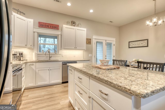 kitchen with stainless steel appliances, a kitchen island, sink, and white cabinets