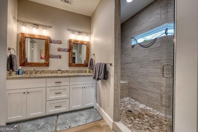 bathroom featuring vanity, wood-type flooring, and a shower with shower door