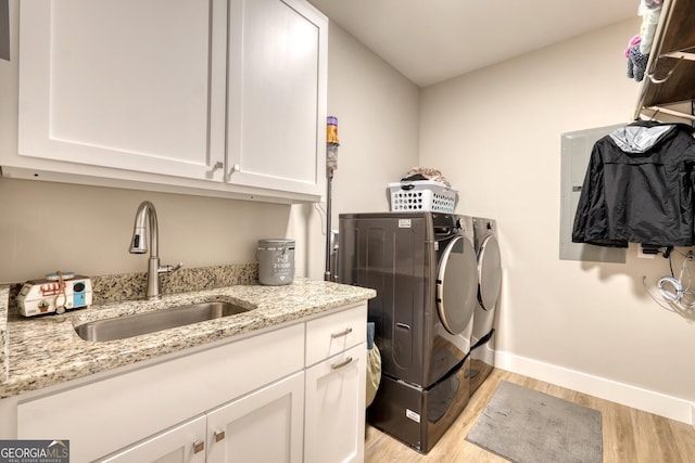 laundry room with sink, washer and clothes dryer, cabinets, and light wood-type flooring