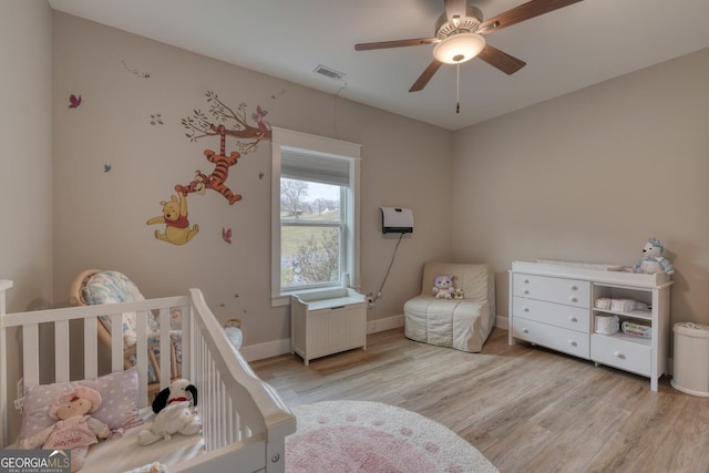 bedroom with a nursery area, radiator, and light hardwood / wood-style floors