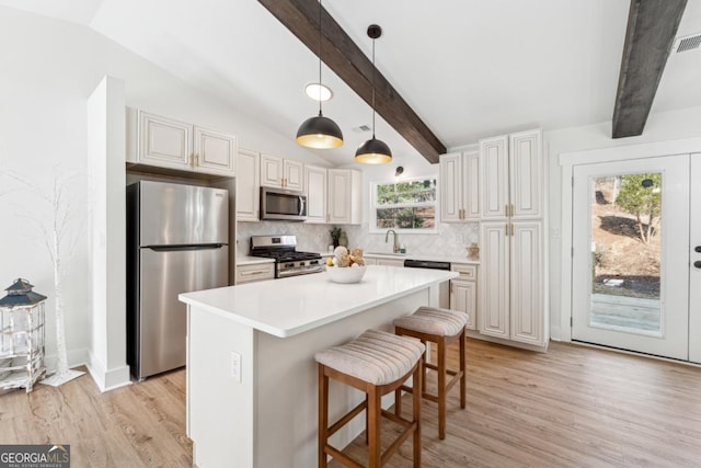 kitchen featuring a breakfast bar, a center island, lofted ceiling with beams, stainless steel appliances, and backsplash